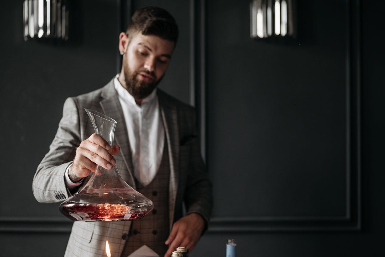 A man elegantly decants wine in a sophisticated indoor setting, creating an atmosphere of luxury and refinement.